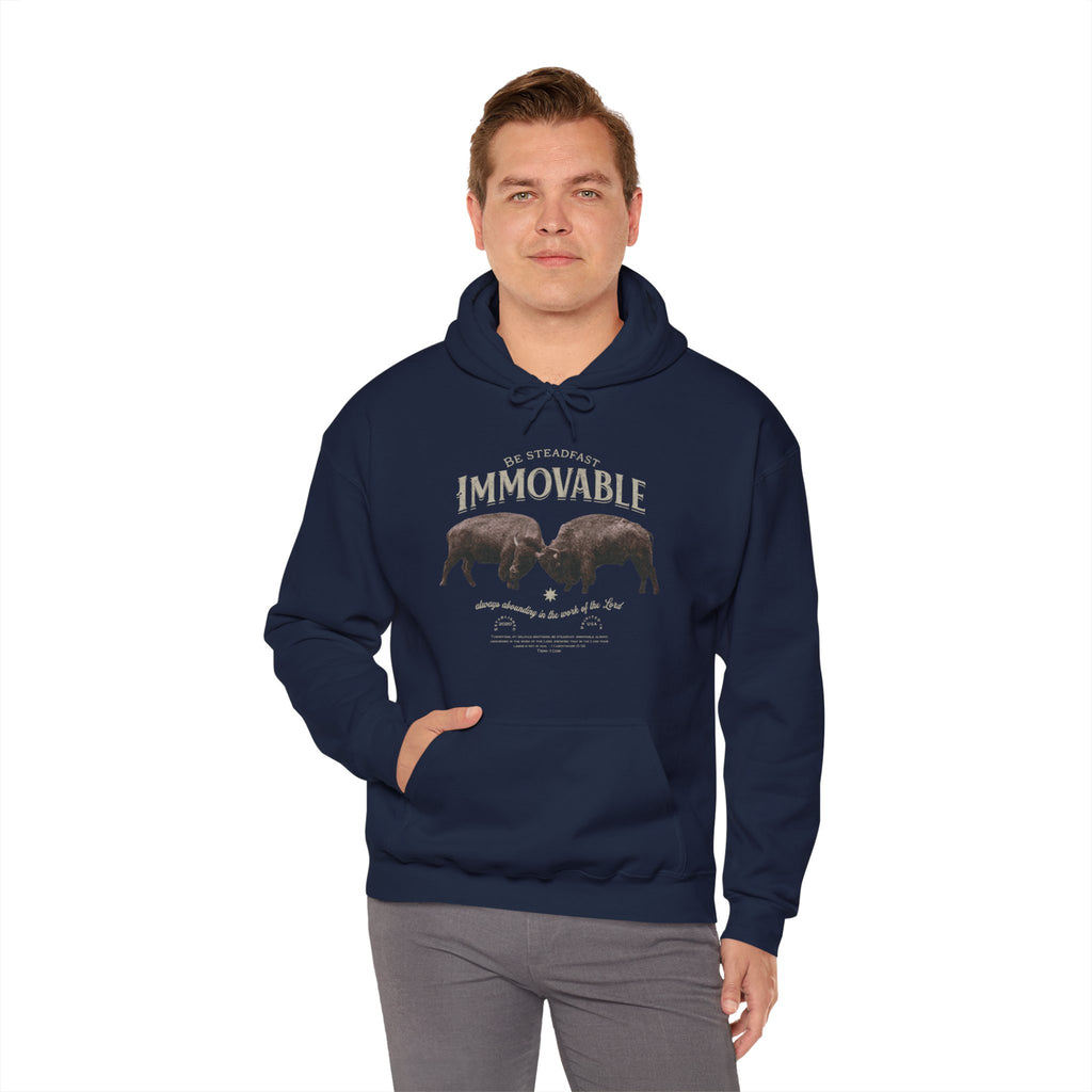Man in Trini-T Ministries Steadfast and Immovable - 1 Corinthians 15:53 Design on Hoodie - Navy Blue in front of white background.