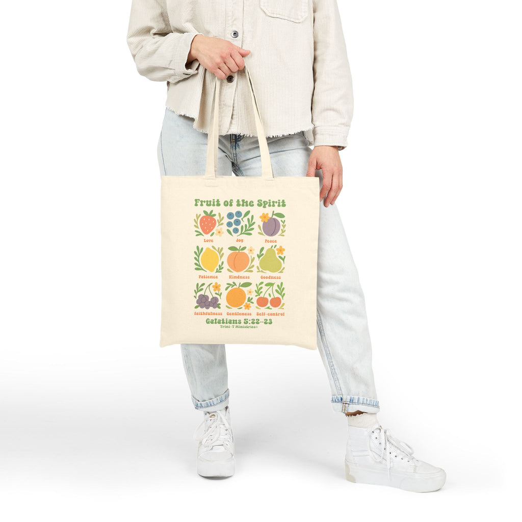 Woman holding a side view of the natural Fruit of the Spirit tote bag.