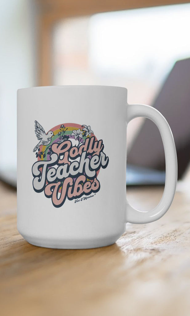 15oz Godly Teacher Vibes mug from Trini-T Ministries on a desk with a computer.