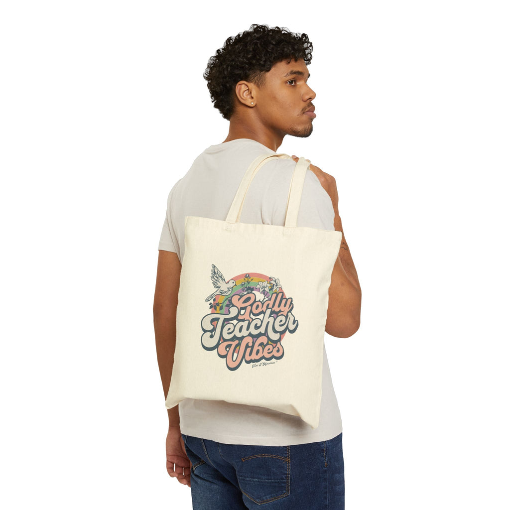 A male model slinging a natural colored version of the Godly Teacher Vibes Tote bag from Trini-T Ministries over his shoulder.