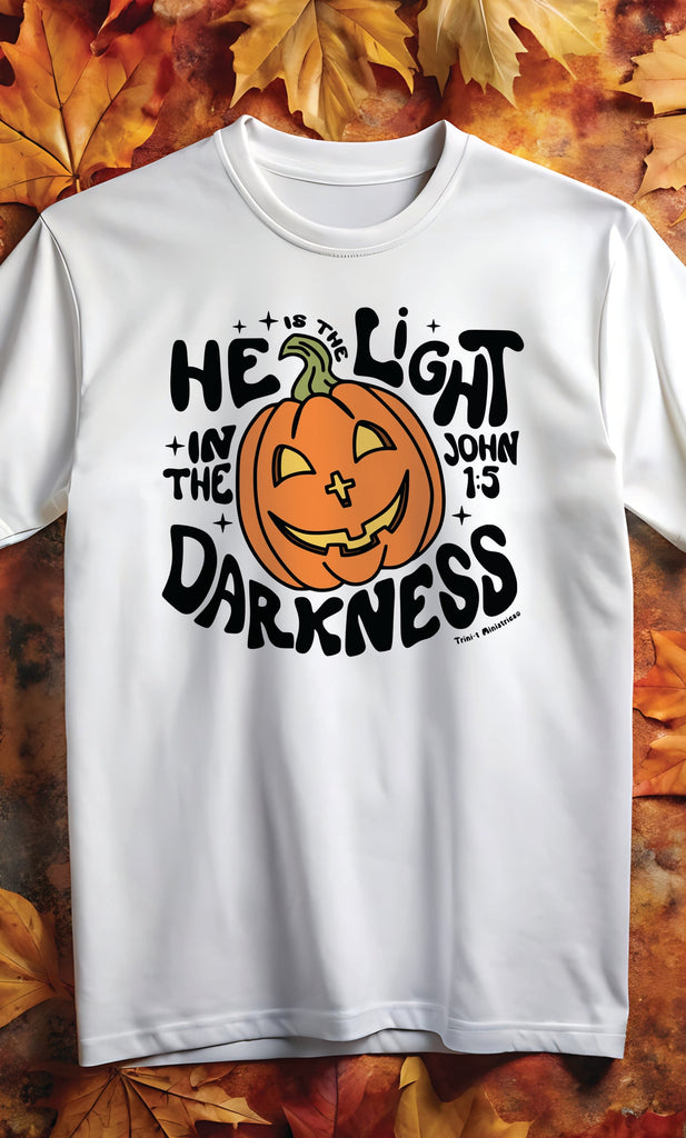 "He is the Light" white Christian t-shirt with pumpkin design referencing John 1:5, perfect for Halloween and sharing the light of Christ.