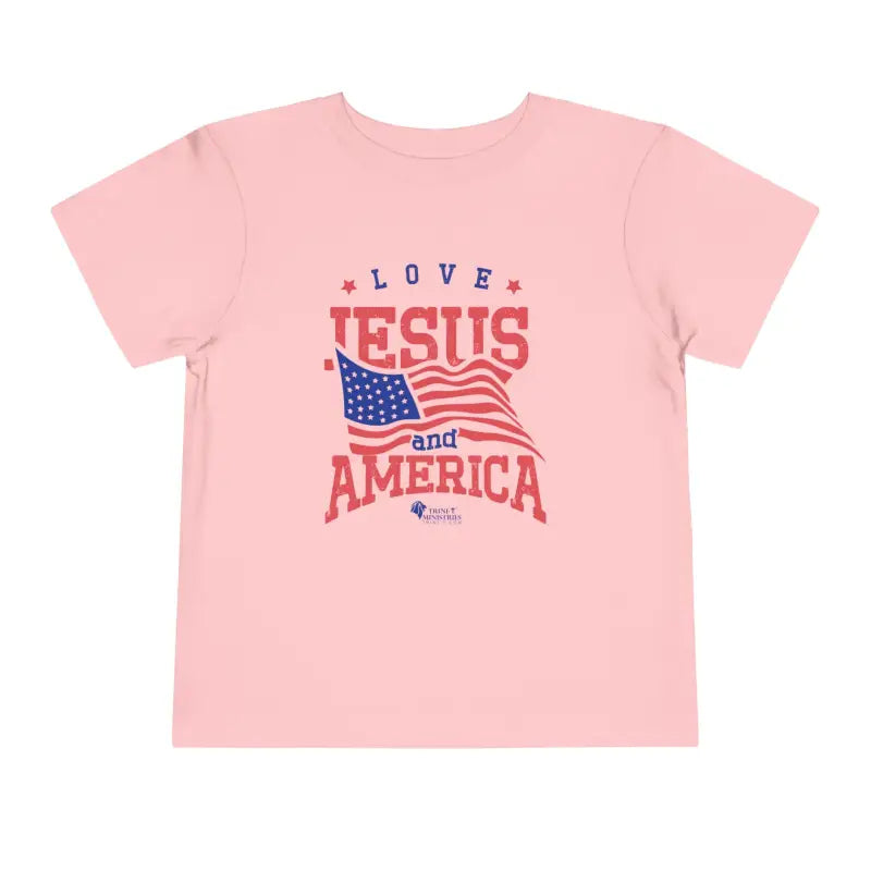 Pink Trini-T Ministries' Love Jesus and America Bella+Canvas 3001T shirt. Get our "Love Jesus and America" Toddler T-Shirt to let your toddler display their faith and patriotism. This delightful and motivating graphic tee is ideal for parents, relatives, and friends who wish to spread the Word of God and express their love for America through their toddler's clothing.