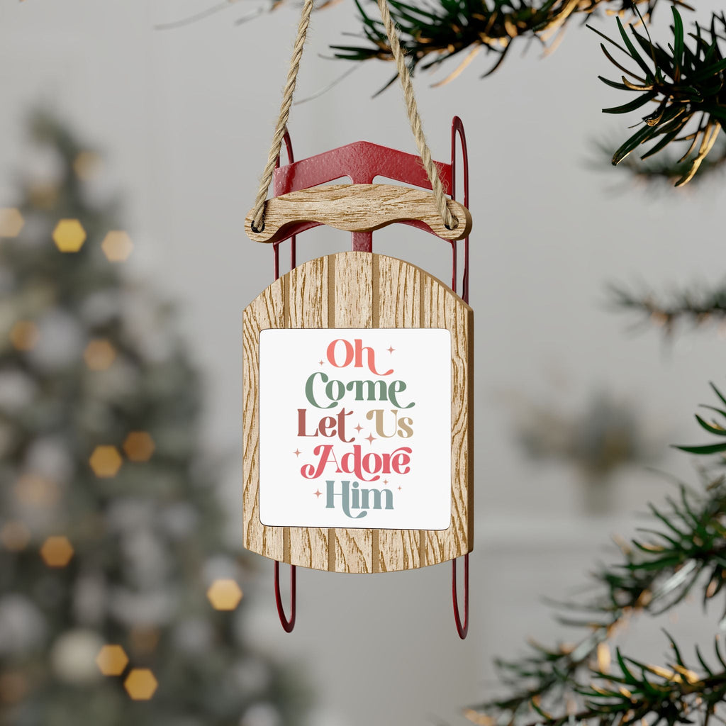 Oh Come Let Us Adore Him Rustic Sled Ornament Hanging from a Tree Outside - The perfect Christian Christmas decoration.