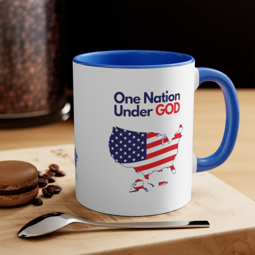 Close-up of a Christian patriotic ceramic mug with blue accents, next to coffee setup, displaying 'One Nation Under God' design.