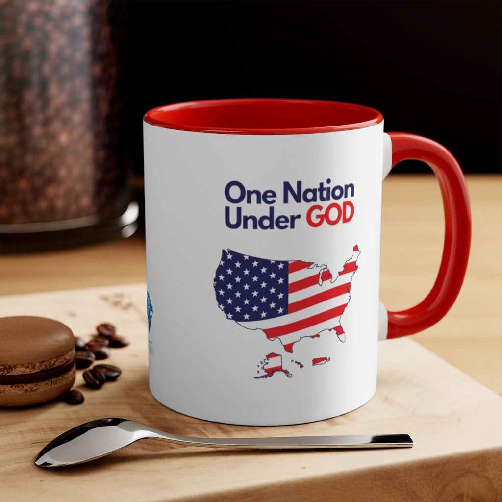 Close-up of a Christian patriotic ceramic mug with red interior and handle, showing 'One Nation Under God' design next to coffee setup.